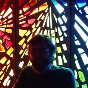 Headshot of author backlit by stained glass.